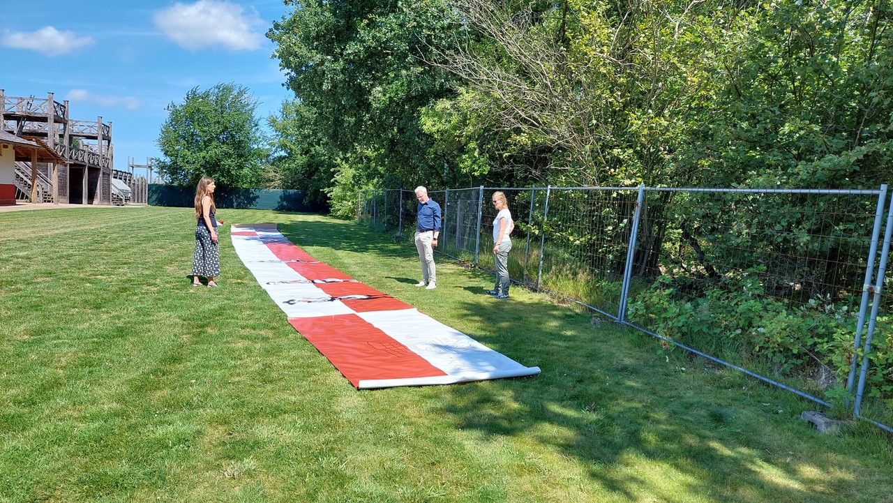 Banner für den Graffiti-Workshop ausgebreitet auf Wiese auf Römerbaustelle.